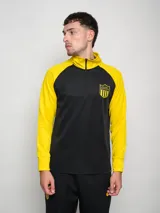 Buzo deportivo negro con mangas amarillas y escudo del Club Atlético Peñarol en el pecho. Tiene cuello alto con cierre parcial.