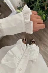 Camisa blanca de manga larga con volados en el frente y en los puños.