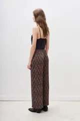 Conjunto de pantalón y kimono con estampado floral en tonos rojos y dorados sobre fondo negro. El pantalón es de corte palazzo y el kimono tiene mangas anchas.