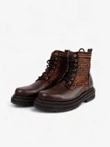 Botas de cuero color marrón con caña media y cordones negros. Presentan un diseño geométrico en la parte superior de la caña y suela track color negro.