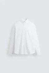 Camisa blanca de algodón, corte regular fit, cuello abotonado, manga larga con puños abotonados, bolsillo en el pecho y cierre frontal con botones.