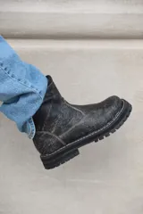 Botas cortas de cuero color gris gastado, con suela track y detalle de hebilla en la caña.
