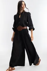 Pantalón de lino negro, súper ancho, de tiro medio-alto con tablas delanteras y elástico en la parte trasera.