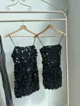 Vestido corto negro con lentejuelas de distintos tamaños, tirantes finos elastizados y cierre en la espalda.