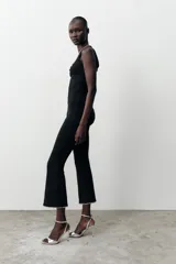 Pantalón negro de tiro alto, corte ajustado y cintura elástica. El ruedo es acampanado y está decorado con perlas.