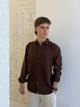 Camisa de lino color marrón, de manga larga con puños abotonados y cierre frontal con botones.