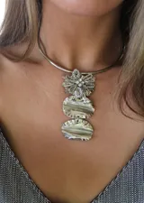 Gargantilla rígida plateada con dijes colgantes: flor de cuentas plateadas y strass, y dos dijes ovalados de nácar.