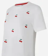 Remera t-shirt blanca de algodón con cuello redondo y mangas cortas. Presenta bordados de cerezas rojas dispersos en el frente.