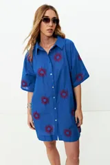 Túnica azul con bordados rojos de soles, cuello camisero, manga corta y corte recto.