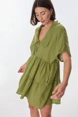 Vestido corto celeste de lino, con cuello tipo polo con detalle de puntilla, mangas cortas y falda escalonada con volantes.