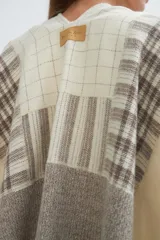 Ruana de lana fina color crudo con diseño de bloques en tonos de gris y beige. Terminación de crochet hecho a mano.