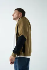 Campera marrón de felpa con capucha, cierre frontal y bolsillos laterales con cierre. Presenta mangas largas negras y logo de la marca estampado en el pecho.