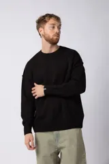 Sweater negro de tejido de punto grueso, corte holgado y cuello redondo.