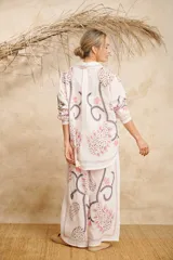 Conjunto de camisa de manga larga con cuello y pantalón palazzo, ambos con estampado de flores y hojas en tonos rosa, gris y marrón sobre fondo blanco.