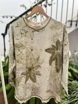 Buzo amplio de frisa liviana de algodón color gris con estampado botánico de hojas en tonos verdes. Tiene cuello redondo y tajos laterales.