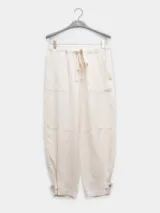 Pantalón estilo cargo color crudo, confeccionado en lino tencel. Cuenta con bolsillos laterales, elástico en la cintura y detalle de Polonio en cobre.