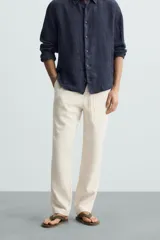 Pantalón verde oscuro de algodón con textura, corte recto, cintura elástica ajustable con cordón, bolsillos laterales y traseros de vivo.