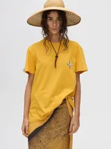 Remera amarilla de corte cuadrado y holgado, con manga corta y estampado de estrella de cuatro puntas en el pecho.