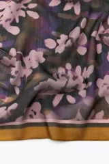 Pañuelo cuadrado de modal con estampado de flores en tonos rosados, morados y verdes sobre fondo oscuro. Tiene un borde liso color ocre.