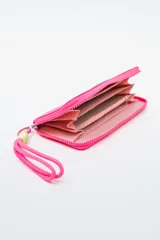 Billetera rectangular color fucsia con cierre perimetral y parche frontal negro con logo. Incluye correa de mano de cordón rosa neón y detalle de ajuste en verde lima.
