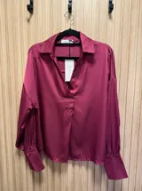 Blusa de seda color fucsia, de corte holgado y mangas largas con puños abotonados.