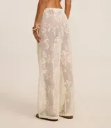 Pantalón de playa blanco de encaje floral con cintura elastizada ajustable con cordón.