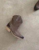 Botas cortas negras de cuero con bordados blancos estilo cowboy.