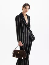 Blazer de jacquard negro con rayas verticales formadas por pequeños estampados de labios. Presenta solapas con vivo, bolsillo relojero y cierre frontal con broche snap dorado.