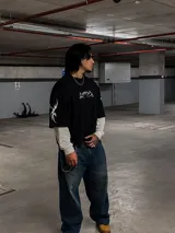 Remera de algodón negra con cuello alto y corte boxy/oversize. Estampa frontal y en mangas con diseño tribal en color blanco.