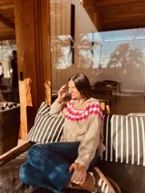 Sweater marrón tejido a mano en mohair con cuello redondo y diseño con motivos geométricos en colores blanco, rosa y celeste.