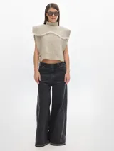 Chaleco de punto color beige con cuello alto y pechera desmontable con flecos.