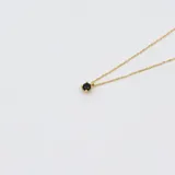 Conjunto de collar doble con cadena de oro amarillo 18k. El collar superior tiene un dije de zafiro engarzado en 4 puntas, y el collar inferior tiene un dije de flor negra con centro de zafiro.