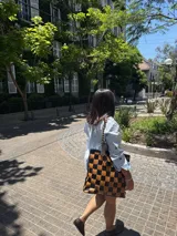 Bolso tote de cuero trenzado a mano, forrado por dentro. Presenta un patrón de cuadros grandes en tonos marrón oscuro y celeste/azul claro.