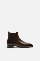 Bota Chelsea de cuero color marrón oscuro, con puntera fina, paneles laterales elásticos y tirador trasero.