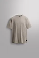Camiseta deportiva color beige confeccionada en tejido con estructura, ligero y elástico en todas direcciones. Tiene cuello redondo, manga corta, costuras planas y logo estampado en el bajo.