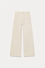 Pantalón de jean color crudo, de tiro alto y corte wide leg. Tiene bolsillos de plastrón en delantero y espalda, trabillas en la cintura y cierre frontal con cremallera y botón metálico.