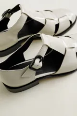 Sandalia roja de cuero vacuno con diseño de tiras entrecruzadas y hebilla lateral. Tiene suela de cuero artesanal y taco bajo.