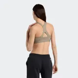 Top deportivo color arena de soporte medio, con breteles finos cruzados en la espalda y logo estampado en el frente.