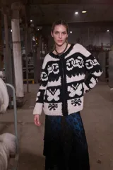 Cardigan tejido de lana color crudo con diseño geométrico en negro, cierre frontal y cuello redondo.