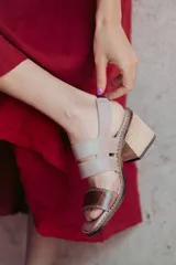 Sandalias de cuero color beige y marrón, con tiras anchas cruzadas en el empeine, puntera descubierta y tacón cuadrado de madera.