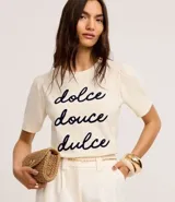Remera color crema de algodón con cuello redondo y mangas cortas abullonadas. Estampa frontal con la frase "dolce douce dulce" en letras cursivas azul marino.