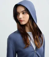 Campera corta de modal color azul, con capucha fija, mangas largas y cierre frontal de cremallera.