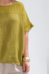 Remera color verde pistacho de lino italiano, con escote a la base, corte amplio y mangas cortas con detalle de flecos.