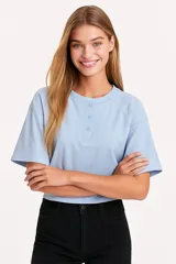 Remera cropped color rosa con cuello redondo, manga 3/4 y cierre frontal con broches.