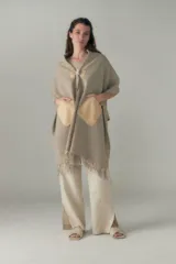 Chal de lana fina sin teñir, con calce en hombros, abrochadura con alamar de fieltro, bolsillos de cuero y terminación con flecos. Diseño exclusivo de Don Baez, hecho en Uruguay.