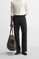 Pantalón negro regular fit confeccionado en tejido de lino. Cintura ajustable con cordón interior, bolsillos frontales y detalle de bolsillos traseros de vivo.