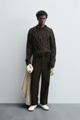 Sweater marrón oscuro de punto con estructura de trenzas, cuello redondo, manga larga y corte regular fit.