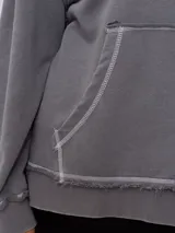 Canguro gris con capucha corta, bolsillo tipo canguro y parche con logo de la marca Rusty en el pecho. Tiene efecto lavado y costuras a la vista.