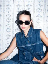 Vestido corto de jean gris con botones frontales, sin mangas, con cuello camisero y bolsillos en el pecho.