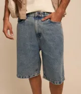Bermuda baggy de jeans con pespunte contrastante, cierre por botón y cremallera, y bolsillos.